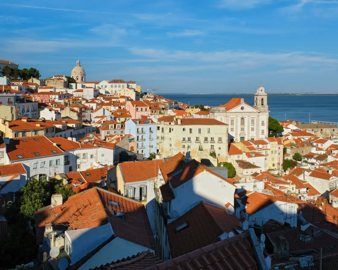 Alfama rooftops and the Tagus seen from Miradouro de Santa Luzia in daylight